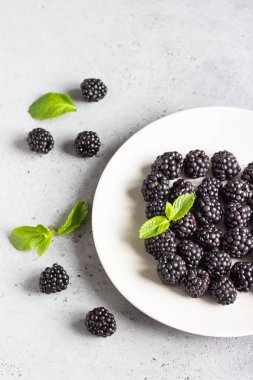 Nane ile bir tabak taze böğürtlen yaprakları açık gri taş renkli. Üstten görünüm, kopya alanı.