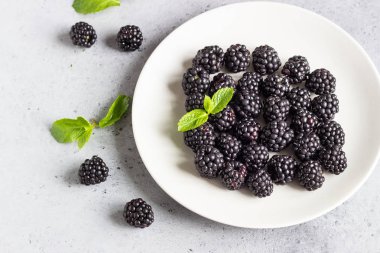 Nane ile bir tabak taze böğürtlen yaprakları açık gri taş renkli. Üstten görünüm, kopya alanı.