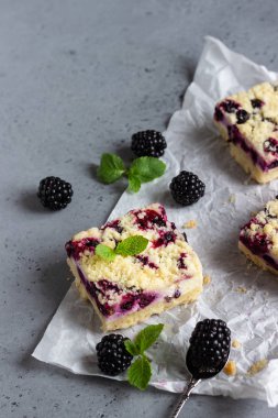 Böğürtlen ile peynirli kek barlar ve streusel ile nane yaprakları pişirme kağıdı beyaz.
