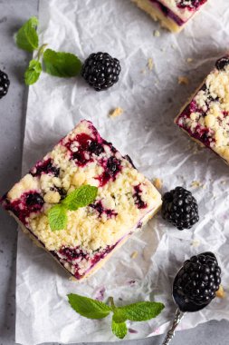Böğürtlen ile peynirli kek barlar ve streusel ile nane yaprakları pişirme kağıdı beyaz.