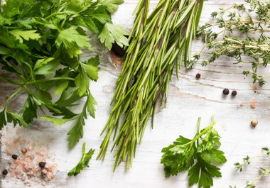 Kekik, biberiye, maydanoz, tuz ve biber bir beyaz tahta kesme tahtası üzerinde. Bahçe ve baharat kokulu otlar.