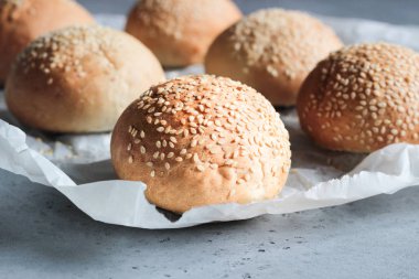 Gri beton zemin üzerine susam ile taze ev yapımı burger buns. Burger ve ev yapımı gıda kavramı. Akşam yemeği ekmek rulo veya mini challah.