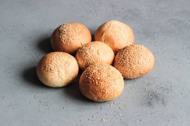 Gri beton zemin üzerine susam ile taze ev yapımı burger buns. Burger ve ev yapımı gıda kavramı. Akşam yemeği ekmek rulo veya mini challah.
