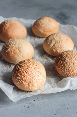Gri beton zemin üzerine susam ile taze ev yapımı burger buns. Burger ve ev yapımı gıda kavramı. Akşam yemeği ekmek rulo veya mini challah.