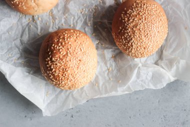 Gri beton zemin üzerine susam ile taze ev yapımı burger buns. Burger ve ev yapımı gıda kavramı. Akşam yemeği ekmek rulo veya mini challah.