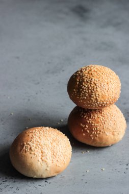 Gri beton zemin üzerine susam ile taze ev yapımı burger buns. Burger ve ev yapımı gıda kavramı. Akşam yemeği ekmek rulo veya mini challah.