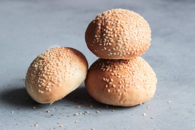 Gri beton zemin üzerine susam ile taze ev yapımı burger buns. Burger ve ev yapımı gıda kavramı. Akşam yemeği ekmek rulo veya mini challah.