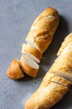 Ekmek (baget) gri beton arka plan üzerinde dilimlenmiş. Kopya alanı ile üstten görünüm.