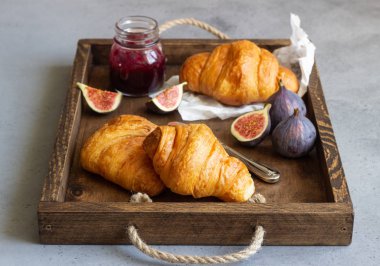 Eski ahşap tepsi ile kruvasan, reçel kavanoz ve taze incir. Kahvaltı saati.