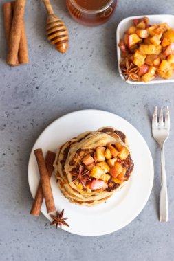 Kızarmış karamelize elma, anason, tarçın ve bal beyaz tabakta lezzetli tatlı ve baharatlı elma krep yığını. Sonbahar kahvaltı. Kopya alanı.