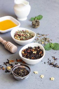 Siyah ve yeşil çay, nane yaprakları ve bal gri beton zemin üzerine kurutulmuş. Üstten görünüm, kopya alanı.