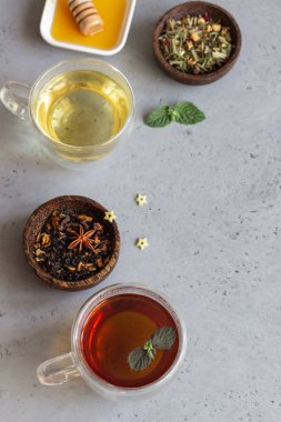 Çift dip cam nane ve ballı gri beton zemin üzerine siyah ve yeşil çay bardak. Kopya alanı.