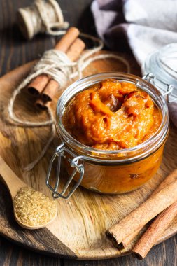 Tarçın ve şeker eski ahşap arka plan, seçici odak üzerinde cam kavanoza kabak ezmesi.