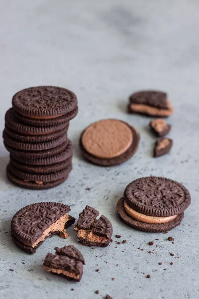 Chocolate sandwich cookies with cocoa cream filing on grey concrete background. Copy space.