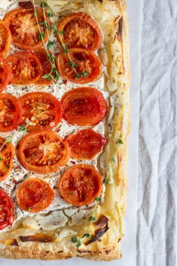 Lezzetli basit domates tart, puf böreği krem peynir veya ricotta ve parşömen kağıt üzerine domates ile tepesinde. Yaz tart. Üstten görünüm. Kopya alanı