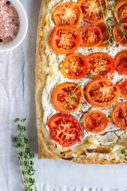 Lezzetli basit domates tart, puf böreği krem peynir veya ricotta ve parşömen kağıt üzerine domates ile tepesinde. Yaz tart. Üstten görünüm. Kopya alanı