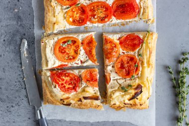 Lezzetli basit domates tart, puf böreği krem peynir veya ricotta ve parşömen kağıt üzerine domates ile tepesinde. Yaz tart. Üstten görünüm. Kopya alanı