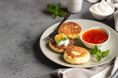 Süzme peynir krep veya reçel, Doğal yoğurt veya ekşi krema ve nane ile börek. Geleneksel Rus mutfağı. Syrniki. Sağlıklı ve diyet kahvaltı.