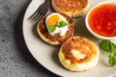 Süzme peynir krep veya reçel, Doğal yoğurt veya ekşi krema ve nane ile börek. Geleneksel Rus mutfağı. Syrniki. Sağlıklı ve diyet kahvaltı.
