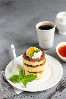 Süzme peynir krep veya reçel, Doğal yoğurt veya ekşi krema ve nane ile börek. Geleneksel Rus mutfağı. Syrniki. Sağlıklı ve diyet kahvaltı.