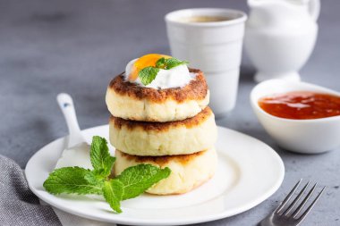 Süzme peynir krep veya reçel, Doğal yoğurt veya ekşi krema ve nane ile börek. Geleneksel Rus mutfağı. Syrniki. Sağlıklı ve diyet kahvaltı.