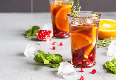 Soğuk limonata veya nar, nane ve turuncu ile şenlikli kokteyl. Gri beton arka plan. Kopya alanı.