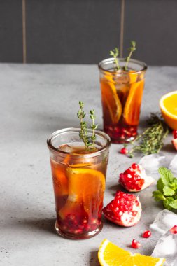Soğuk limonata veya nar, nane ve turuncu ile şenlikli kokteyl. Gri beton arka plan. Kopya alanı.