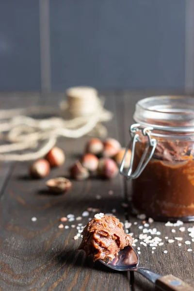 Ev yapımı tuzlu karamel veya çikolata Yapıştır serpilir tuz ve eski ahşap zemin üzerine fındık ile cam kavanozda.