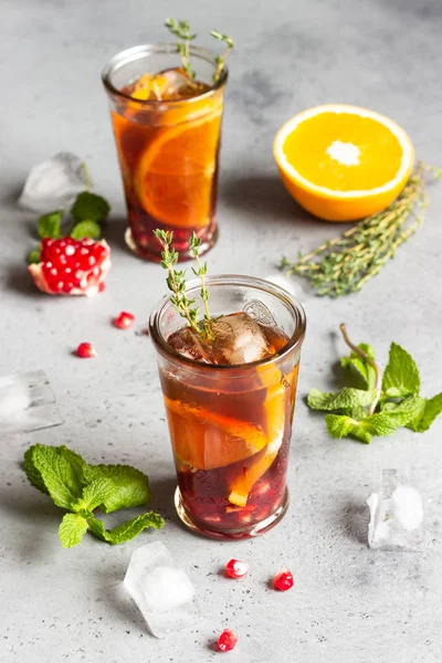 Soğuk limonata veya nar, nane ve turuncu ile şenlikli kokteyl. Gri beton arka plan. Kopya alanı.