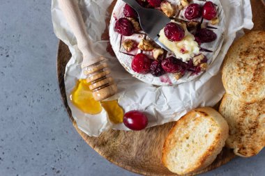 Kızılcık, ceviz, bal ve parşömen kağıt üzerine kekik ile pişmiş peyniri. Peynir Brie türü. Gri kayrak, taş veya beton tablo. Kopya alanı.