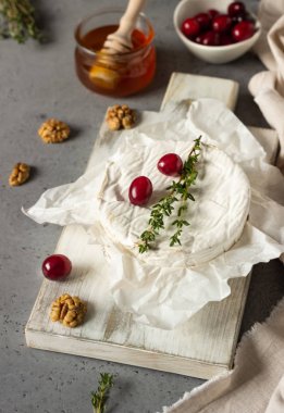 Kızılcık, ceviz, bal ve parşömen kağıt üzerine kekik ile pişmiş peyniri. Peynir Brie türü. Gri kayrak, taş veya beton tablo. Kopya alanı.