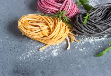 Renkli taze çiğ ev yapımı makarna makarna un gri kayrak, taş veya beton tablo ile çeşitli. Üstten görünüm. Gıda arka plan. Metin için yer kopyalayın.