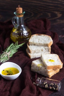 Koyu kahverengi arka plan üzerine dilimlenmiş taze ekmek ve sızma zeytinyağı 