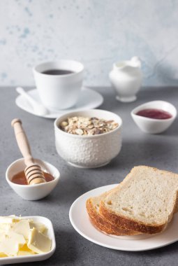 Tereyağı ve kahve, granola, bal ve reçel gri taş arka plan üzerinde fincan ile kahvaltıda ekmek. 
