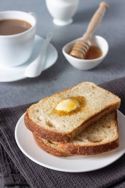 Dilim tost ekmek ve tereyağı gri taş zemin üzerine bal ile