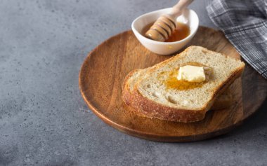 Dilim tost ekmek ve tereyağı gri taş zemin üzerine bal ile