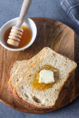 Dilim tost ekmek ve tereyağı gri taş zemin üzerine bal ile