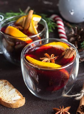 Cam bardak sıcak mulled şarap veya baharat ve koyu kahverengi zemin üzerine portakal parçaları ile gluhwein. Noel mulled şarap. Geleneksel içki kış tatil. Kopya alanı.