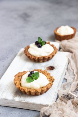 Mini tart (tartlets) ile krem şanti veya muhallebi ve taze çilek nane ile servis. Ev yapımı tatlılar. Gri arka plan. Kopya alanı.