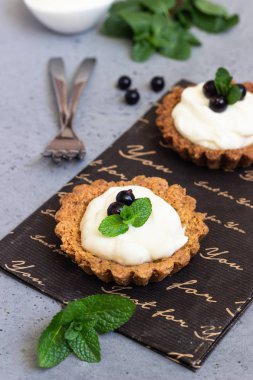 Mini tart (tartlets) ile krem şanti veya muhallebi ve taze çilek nane ile servis. Ev yapımı tatlılar. Gri arka plan. Kopya alanı.