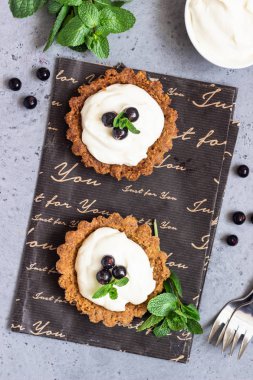 Mini tart (tartlets) ile krem şanti veya muhallebi ve taze çilek nane ile servis. Ev yapımı tatlılar. Gri arka plan. Kopya alanı.