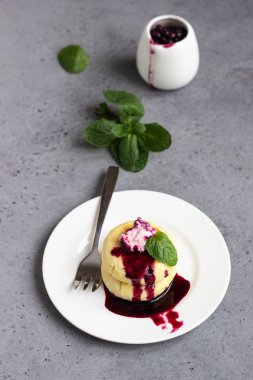 Süzme peynir krep veya yaban mersini sosu ve nane ile börek. Geleneksel Rus mutfağı. Syrniki. Sağlıklı ve diyet kahvaltı.