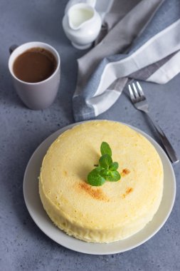 Gri bir plaka üzerinde nane ile Japon pamuk cheesecake. Kabuk peynirli kek. Gri taş veya beton arka plan. Seçici odak, kopya alanı. 