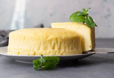 Gri bir plaka üzerinde nane ile Japon pamuk cheesecake. Kabuk peynirli kek. Gri taş veya beton arka plan. Seçici odak, kopya alanı. 