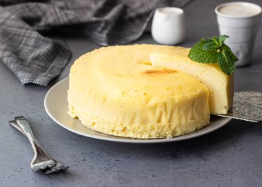 Gri bir plaka üzerinde nane ile Japon pamuk cheesecake. Kabuk peynirli kek. Gri taş veya beton arka plan. Seçici odak, kopya alanı. 