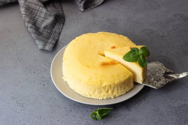 Gri bir plaka üzerinde nane ile Japon pamuk cheesecake. Kabuk peynirli kek. Gri taş veya beton arka plan. Seçici odak, kopya alanı. 