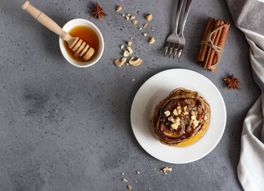 Kaju fıstığı, bal, tarçın ve beyaz bir tabakta anason ile Krep. Mükemmel kahvaltı. Gri beton arka plan. Kopyalama alanı.