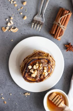 Kaju fıstığı, bal, tarçın ve beyaz bir tabakta anason ile Krep. Mükemmel kahvaltı. Gri beton arka plan. Kopyalama alanı.