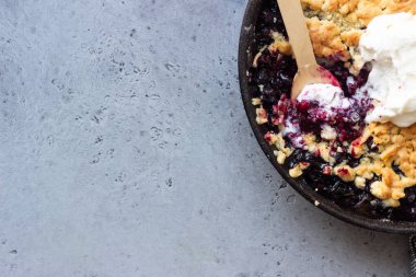 Siyah frenk üzümü kek dökme demir tavada vanilyalı dondurma ile. Sağlıklı gıda kavramı. Gri taş arka plan. Üstten görünüm. Kopya alanı.