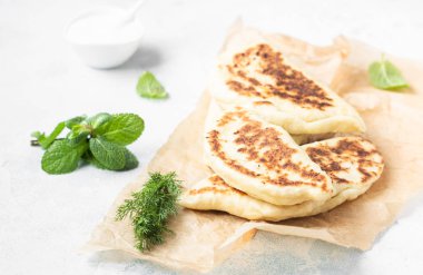 Taze ot ve yoğurt sos ile düz ekmek kızartma tavası pişmiş. Khychiny veya qutab - geleneksel beyaz veya Azeri gözleme.